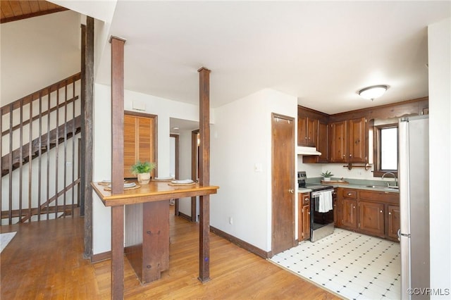 kitchen with light wood-type flooring, electric range, white fridge, and sink