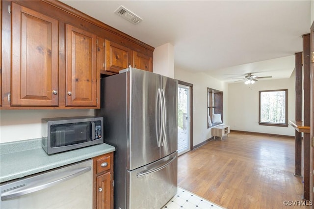 kitchen with light wood-type flooring, stainless steel appliances, and ceiling fan