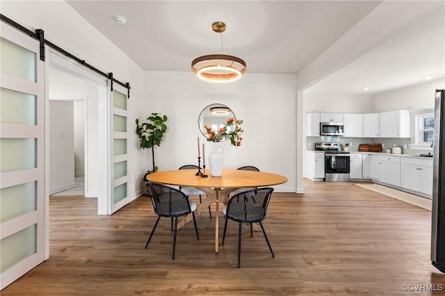 dining space featuring built in shelves, wood-type flooring, and a barn door