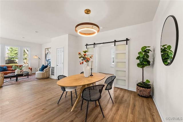 dining space featuring wood-type flooring and a barn door