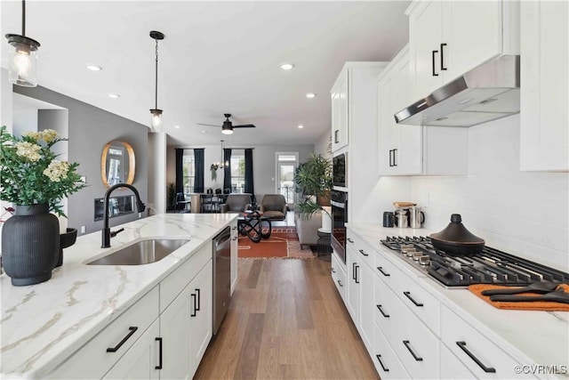 kitchen featuring pendant lighting, appliances with stainless steel finishes, white cabinetry, a sink, and under cabinet range hood