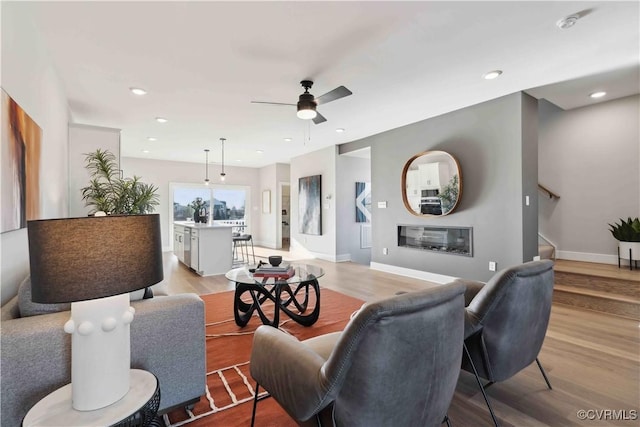 living room with light wood-type flooring, stairway, and a glass covered fireplace