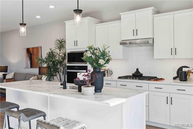 kitchen featuring under cabinet range hood, stainless steel gas stovetop, white cabinets, and oven