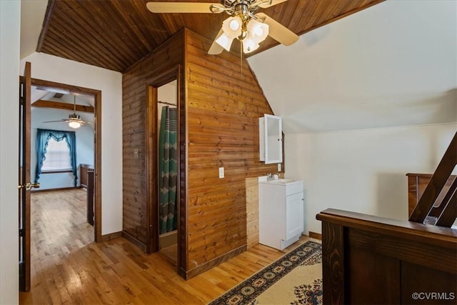 hall featuring wood walls, sink, vaulted ceiling, light wood-type flooring, and wood ceiling