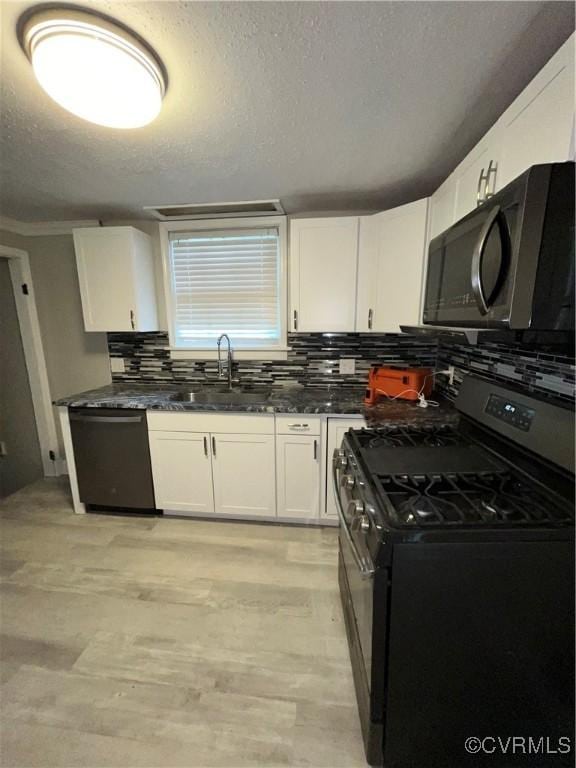 kitchen with sink, tasteful backsplash, a textured ceiling, white cabinets, and black appliances