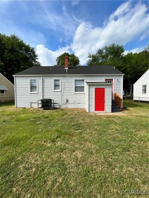 rear view of property with central AC unit and a yard