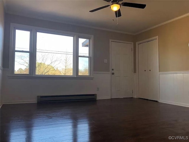 empty room featuring ornamental molding, dark hardwood / wood-style floors, ceiling fan, and a baseboard heating unit