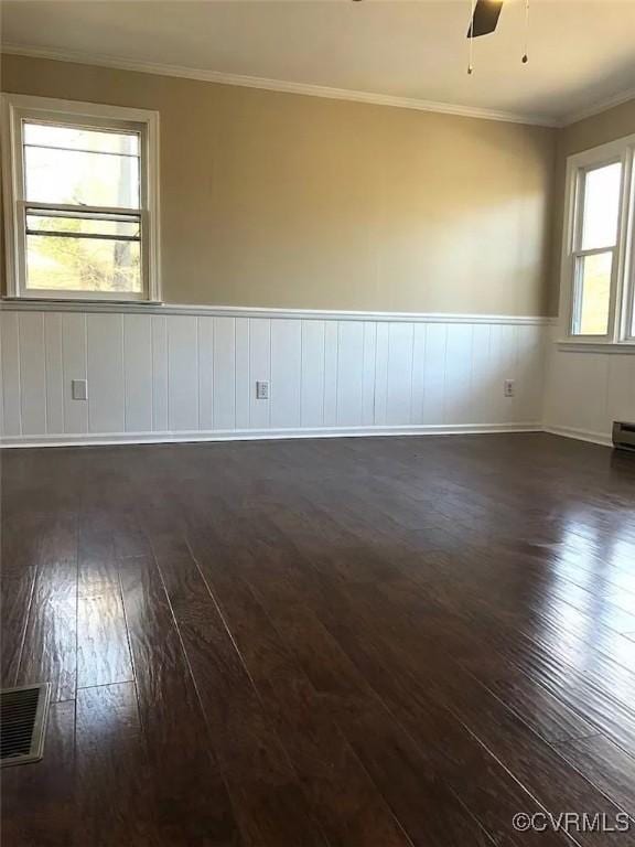 unfurnished room with plenty of natural light, ceiling fan, ornamental molding, and dark wood-type flooring