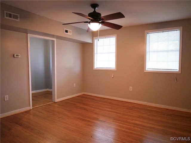 unfurnished bedroom featuring multiple windows, ceiling fan, and hardwood / wood-style flooring