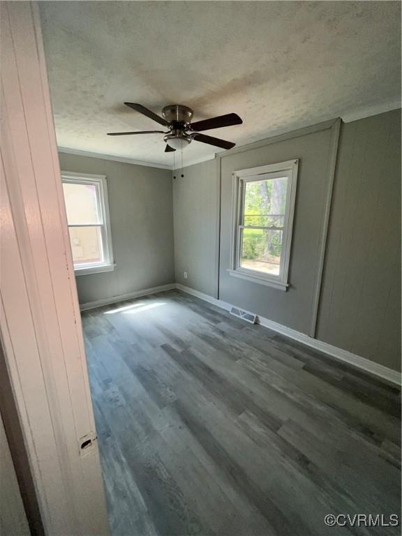 spare room with a textured ceiling, crown molding, ceiling fan, and dark wood-type flooring