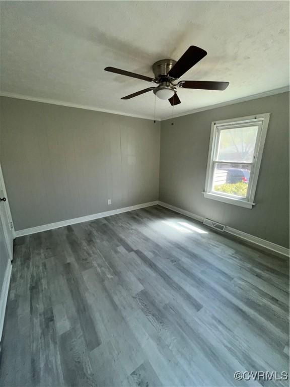 empty room featuring ceiling fan, wood-type flooring, and ornamental molding