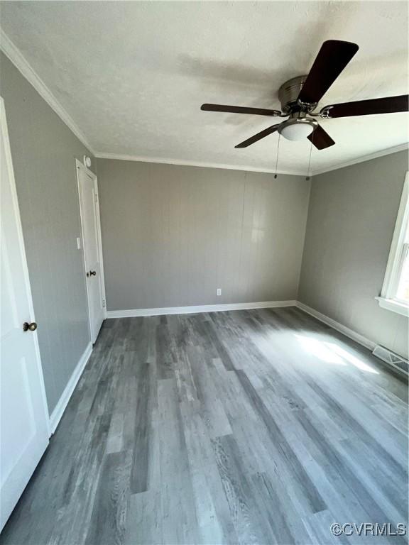 empty room with ceiling fan, wood-type flooring, and crown molding