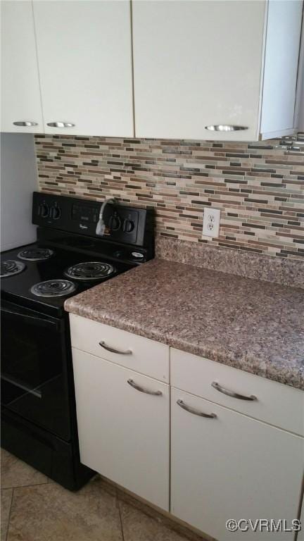 kitchen featuring black electric range oven, white cabinetry, light tile patterned floors, and tasteful backsplash