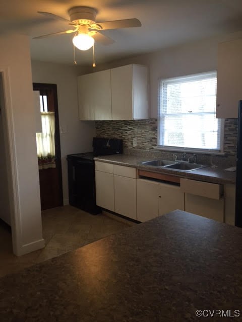 kitchen with backsplash, black range with electric cooktop, ceiling fan, sink, and white cabinetry