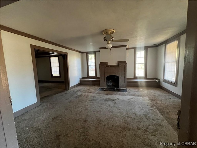 unfurnished living room featuring carpet flooring, a wealth of natural light, crown molding, and ceiling fan