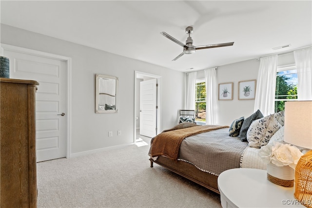 bedroom with ceiling fan, light colored carpet, and connected bathroom