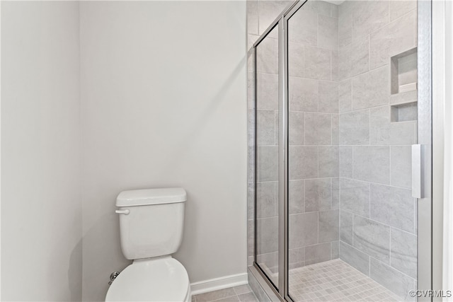 bathroom with tile patterned flooring, toilet, and a shower with door