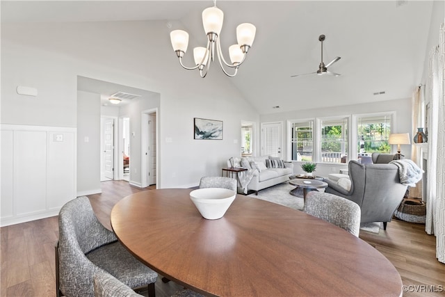 dining space with ceiling fan with notable chandelier, light hardwood / wood-style floors, and high vaulted ceiling