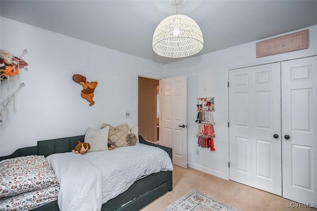 bedroom featuring a chandelier, light colored carpet, and a closet