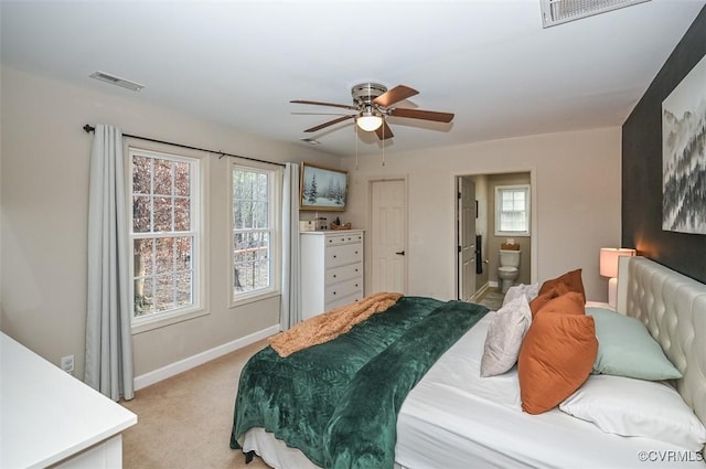 carpeted bedroom with multiple windows, ceiling fan, and ensuite bathroom