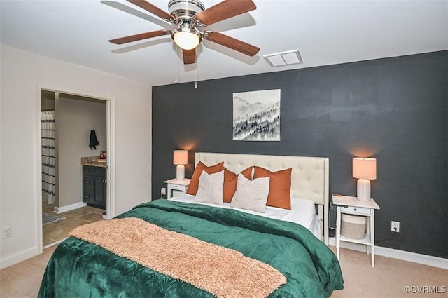 bedroom featuring connected bathroom, light colored carpet, and ceiling fan