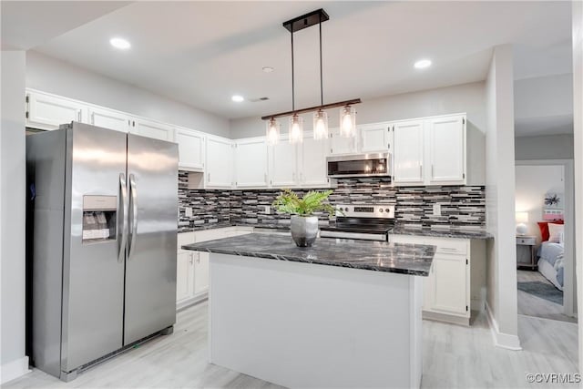 kitchen featuring hanging light fixtures, white cabinets, backsplash, a kitchen island, and appliances with stainless steel finishes