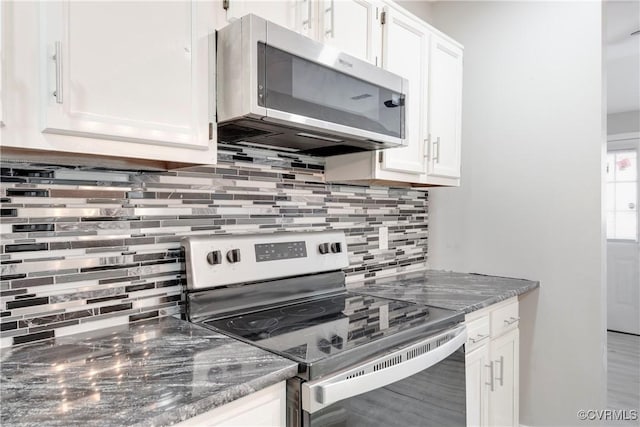 kitchen with stainless steel appliances, white cabinetry, tasteful backsplash, and dark stone countertops