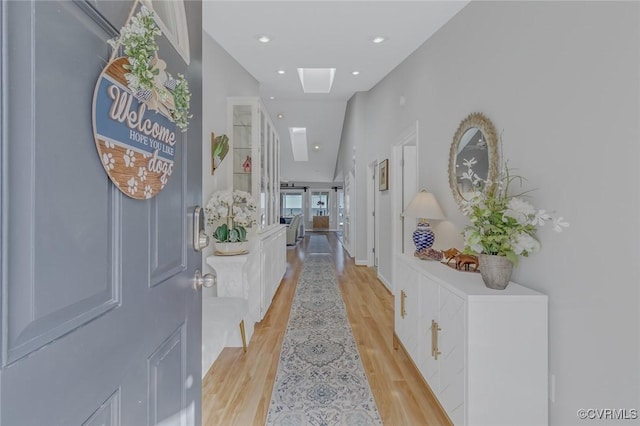 corridor with a skylight and light hardwood / wood-style floors