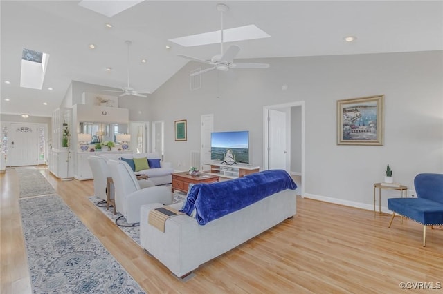 living room featuring a skylight, high vaulted ceiling, ceiling fan, and light hardwood / wood-style floors