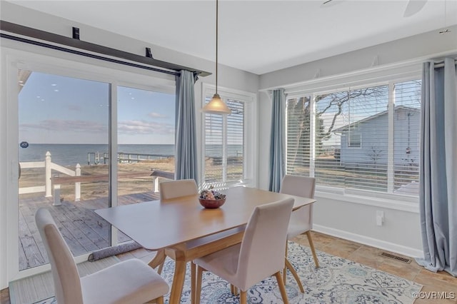 tiled dining space with a water view and a healthy amount of sunlight