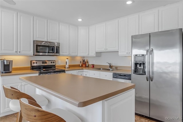 kitchen featuring stainless steel appliances, sink, a center island, white cabinetry, and a breakfast bar area