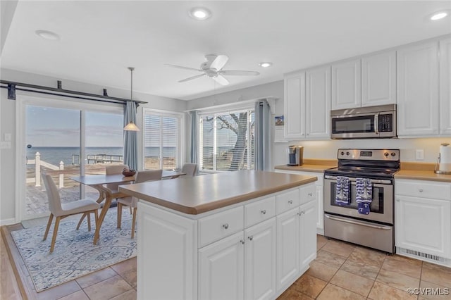 kitchen featuring white cabinets, a center island, pendant lighting, and stainless steel appliances