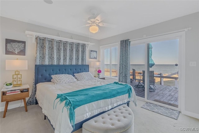 carpeted bedroom featuring access to exterior, ceiling fan, and a water view