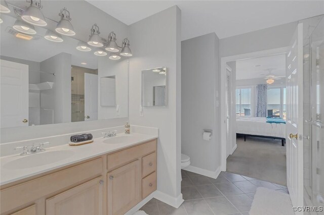 bathroom with tile patterned floors, vanity, a shower with door, ceiling fan, and toilet