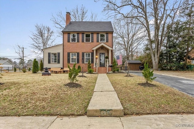 view of front of house with a storage shed and a front yard