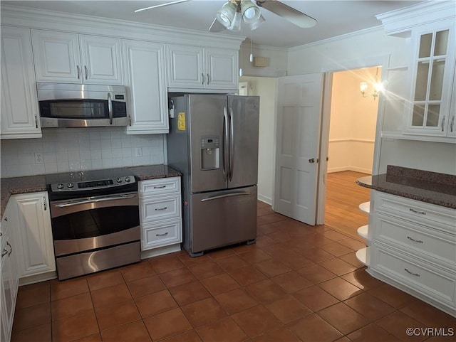 kitchen with stainless steel appliances, dark stone counters, and white cabinetry