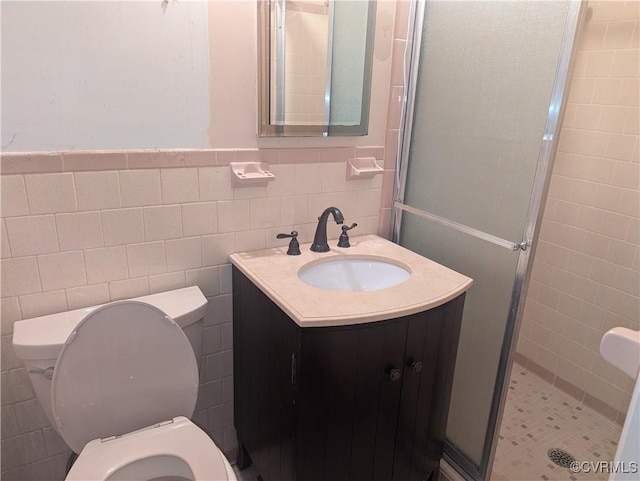 bathroom with tile walls, an enclosed shower, vanity, and toilet