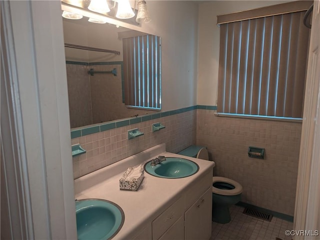 bathroom with tile walls, tile patterned flooring, toilet, and vanity