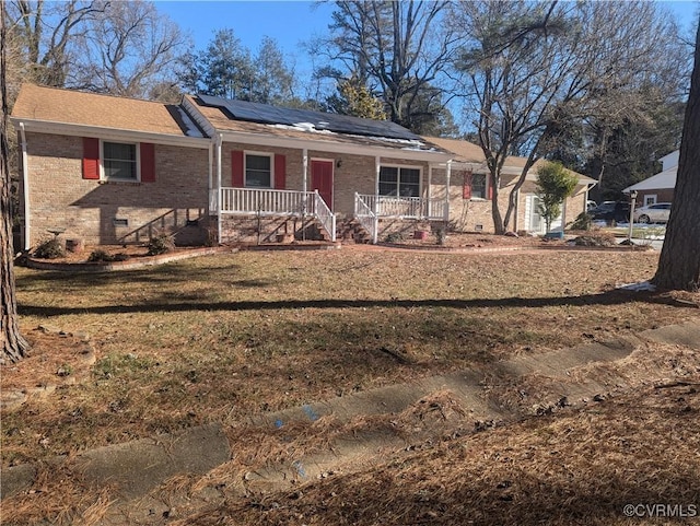 ranch-style home with a porch, solar panels, and a front yard