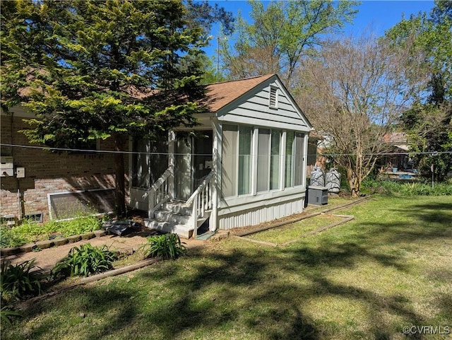 view of side of home featuring a yard and a shingled roof