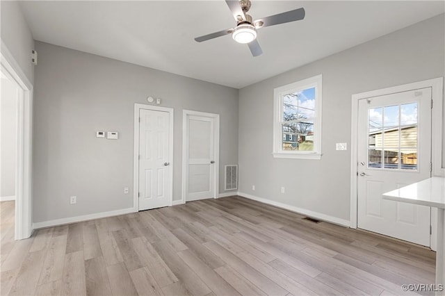 interior space featuring ceiling fan, light wood-type flooring, and multiple closets