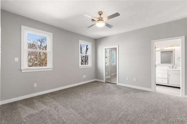 unfurnished bedroom with ceiling fan, sink, light carpet, and ensuite bath