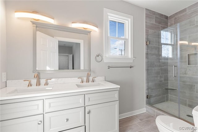 bathroom featuring vanity, a shower with door, toilet, and plenty of natural light