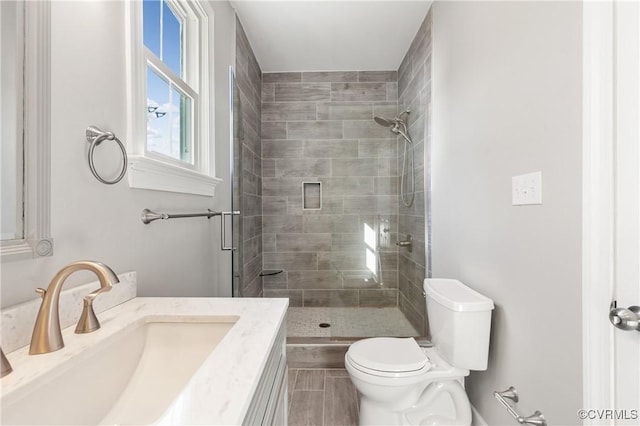 bathroom featuring vanity, a shower with shower door, and toilet