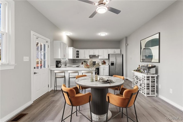 kitchen featuring white cabinetry, sink, stainless steel appliances, light hardwood / wood-style flooring, and kitchen peninsula