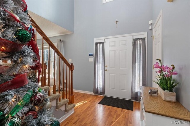 foyer with a healthy amount of sunlight, stairs, light wood-style flooring, and a towering ceiling