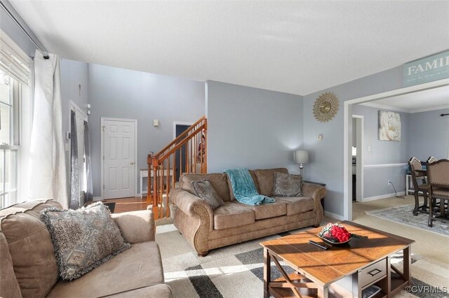 living room featuring carpet floors, baseboards, and stairway