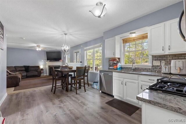 kitchen featuring stainless steel dishwasher, decorative backsplash, ceiling fan, white cabinets, and a sink