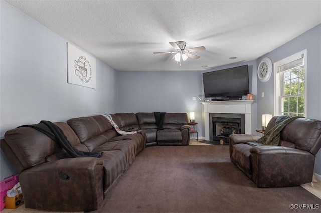 living area with a ceiling fan, a textured ceiling, a fireplace with flush hearth, and carpet