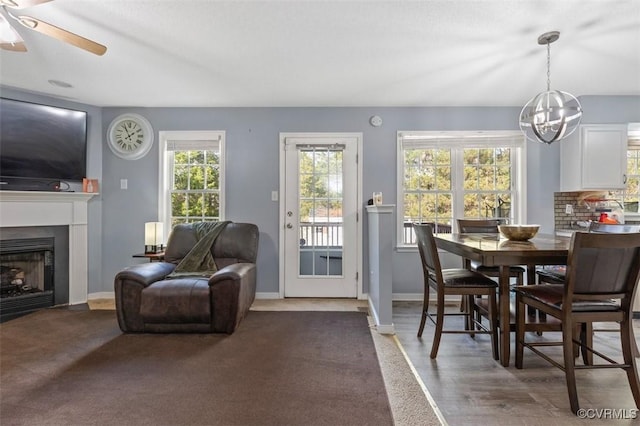 dining room with baseboards, a fireplace with flush hearth, and ceiling fan